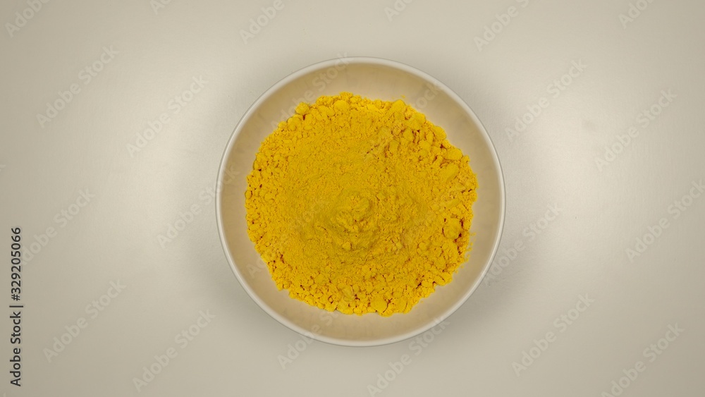 TOP VIEW: Curcuma powder in a white dish TOP VIEW: Curcuma powder in a white dish