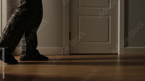 Aged man in pajamas walks on a home in the night