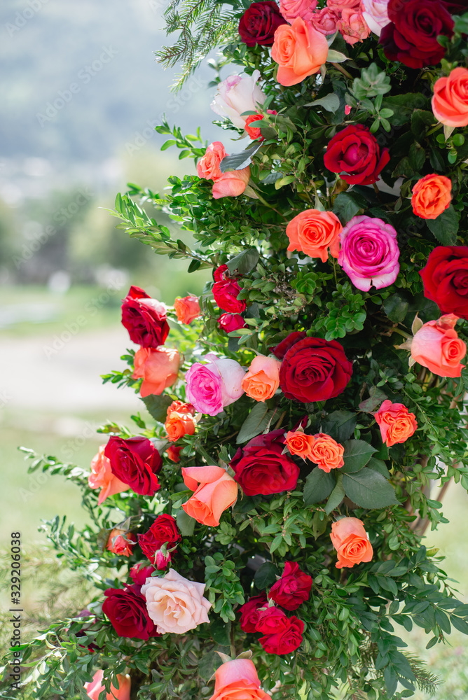 Close up of wedding decorations with beautiful flowers red and yellow roses for ceremony outdoors. Summer floral composition. Elegant arrangement floristics setting. Party decor detail