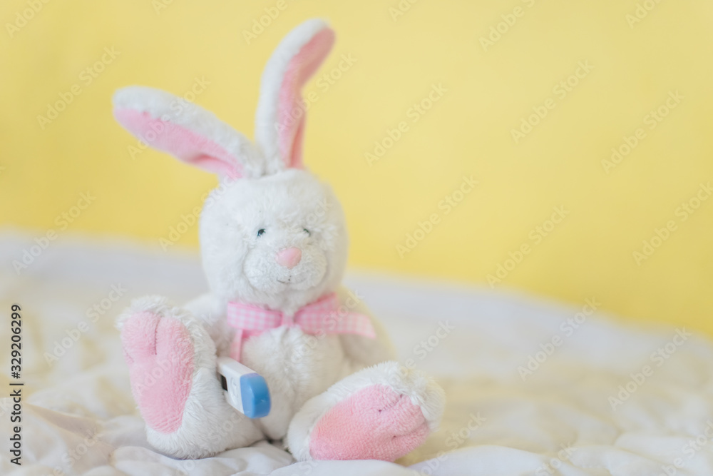 Toy Hare with electronic thermometer under paw. Measuring high temperature of children with influenza and viruses, coronavirus. Medicine concept. Toy Hare with electronic thermometer under paw. Measuring high temperature of children with influenza and viruses, coronavirus. Medicine concept.