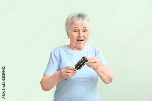 Senior woman with hair loss problem on color background