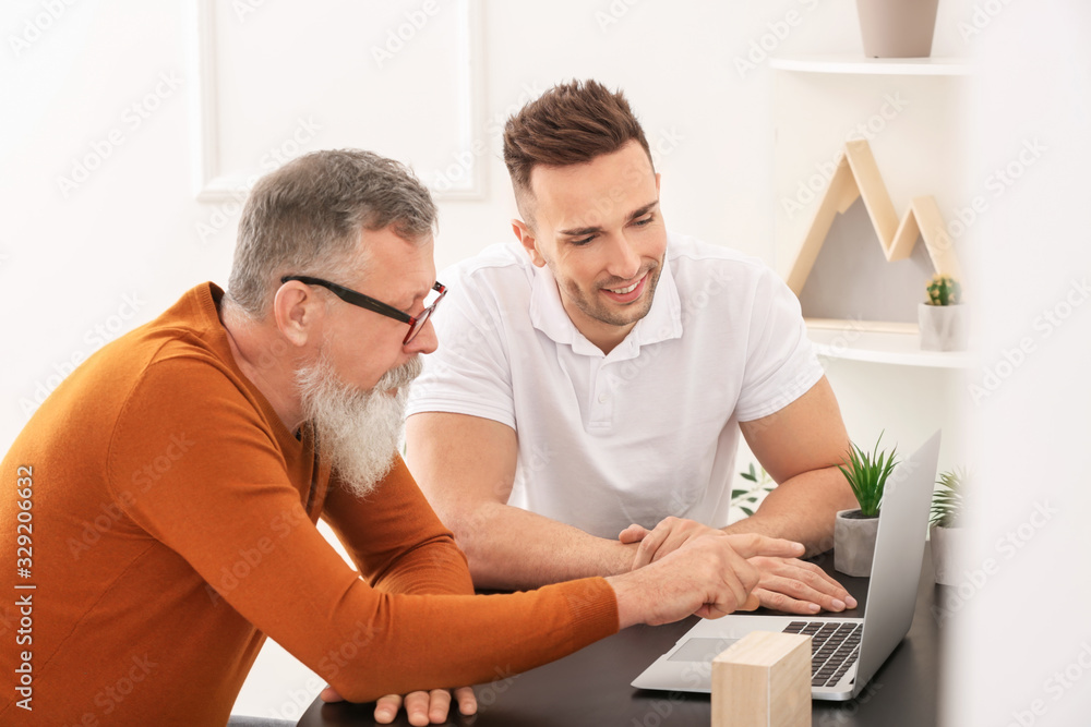 Young man teaching his father to handle with modern computer Young man teaching his father to handle with modern computer