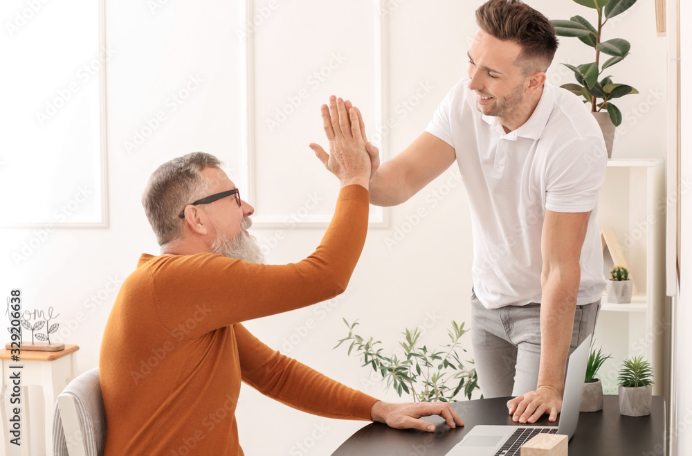 Fototapeta premium Young man teaching his father to handle with modern computer