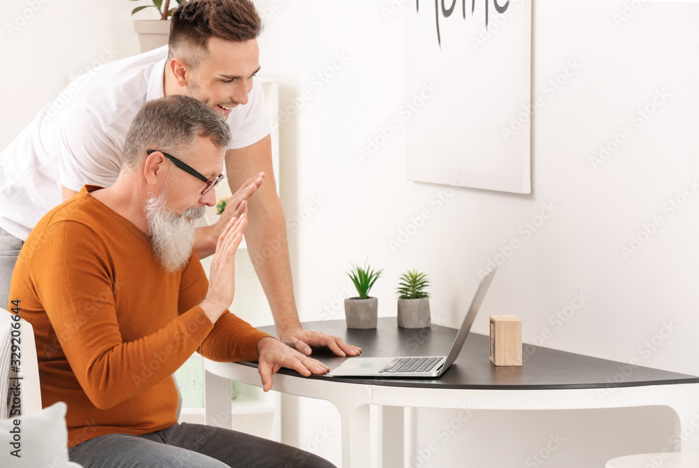 Young man teaching his father to handle with modern computer Young man teaching his father to handle with modern computer