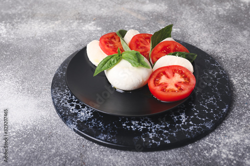 Mozzarella cheese with tomatoes and basil on grey background