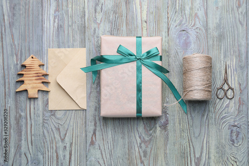 Beautiful gift for Christmas with envelope and supplies on wooden background