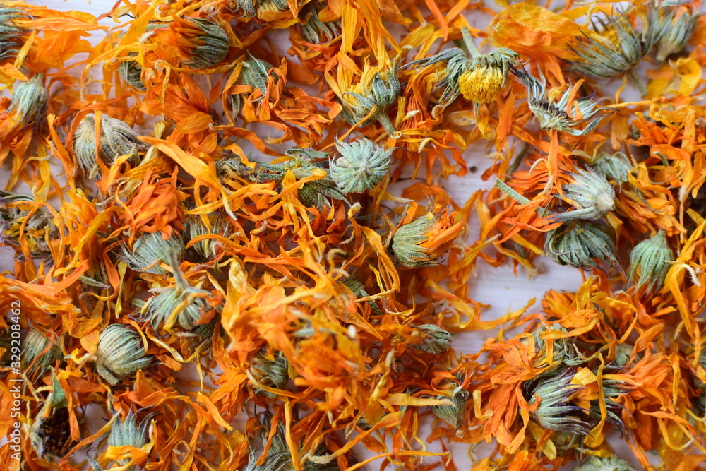 Petals of chopped dried calendula, displayed in containers on white wooden background Petals of chopped dried calendula, displayed in containers on white wooden background