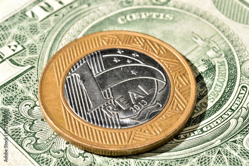 Close up de Moeda de 1 Real brasileiro acima de uma nota de Dólar americano photo