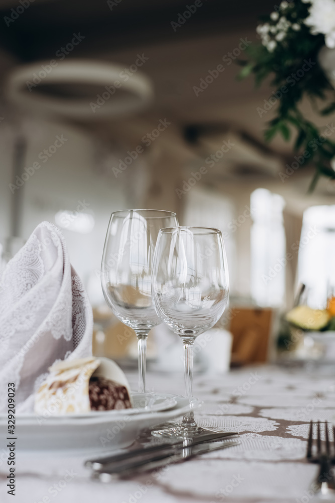 Server table plate knife fork and wine glasses at the banquet. Luxurious elegant dinner at the table in the restaurant. Holiday table decoration Server table plate knife fork and wine glasses at the banquet. Luxurious elegant dinner at the table in the restaurant. Holiday table decoration