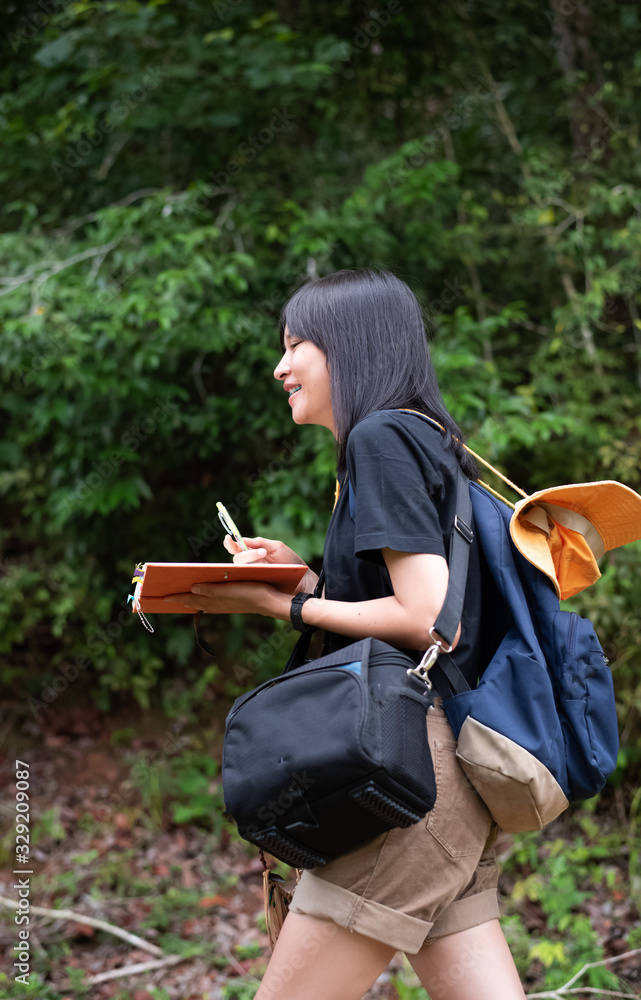 Obraz premium The beautiful woman backpack and holdking book in hand,walking in a park,relax time,on holiday