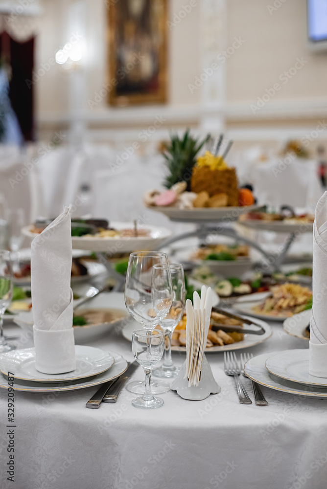 Server table plate knife fork and wine glasses at the banquet. Luxurious elegant dinner at the table in the restaurant. Holiday table decoration Server table plate knife fork and wine glasses at the banquet. Luxurious elegant dinner at the table in the restaurant. Holiday table decoration