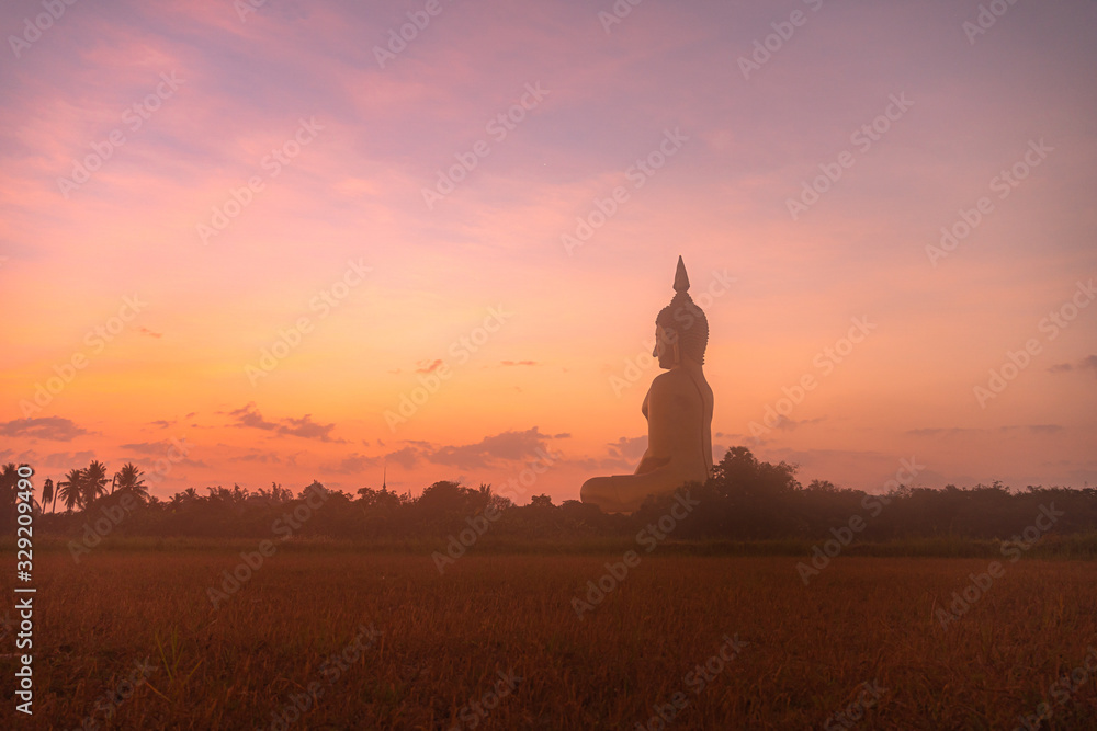 sunrise above the great Buddha of Thailand at wat Muang Ang Thong Thailand. .The largest Buddha statue in the world Can be seen from afar Surrounded by rice fields.