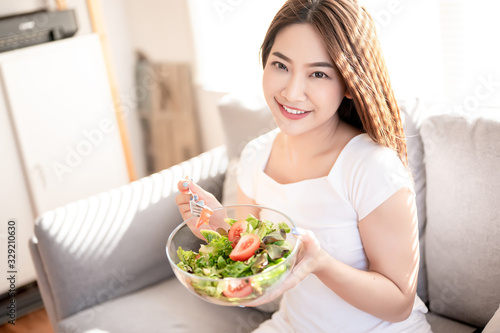 Beautiful young asian eating salad with big smile happy beaming face in seamless blue isolated background. Diet healthy concept. Her face and skin are healthy, fresh, bright and youthful.