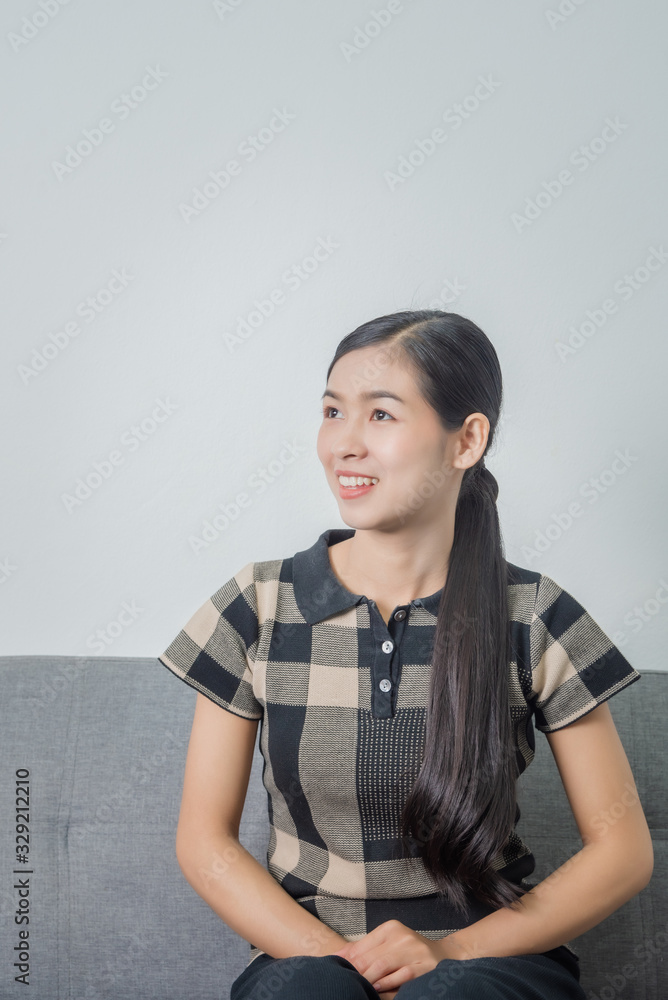 Close-up portrait of a cute asian female student girl while sitting on sofa. Wide smile, happiness.