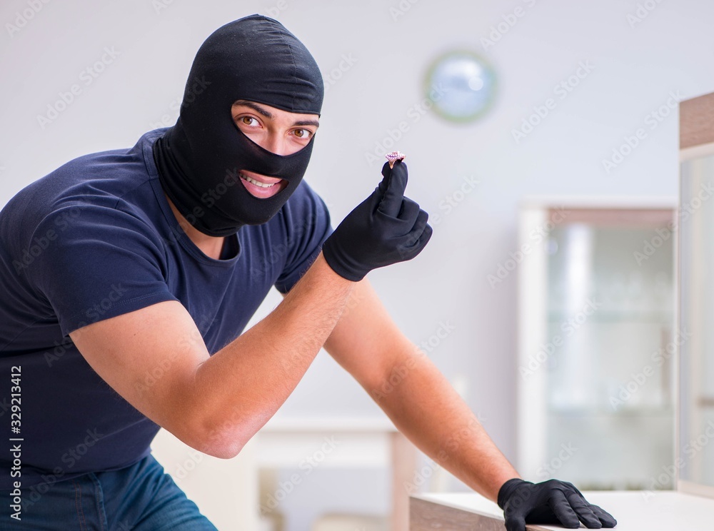 Robber wearing balaclava stealing valuable things Robber wearing balaclava stealing valuable things