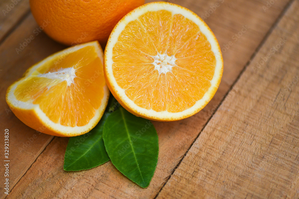 Fresh orange slice half and orange leaf healthy fruits harvest concept - Orange fruit on wooden background Fresh orange slice half and orange leaf healthy fruits harvest concept - Orange fruit on wooden background