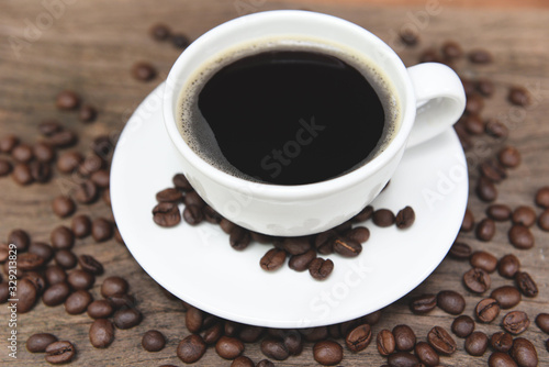 Coffee cup and coffee beans on table - black coffee in white mug on wooden background