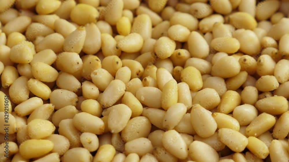 Pine nuts background. Unshelled cedar seeds, closeup. Rotate Pine nuts background. Unshelled cedar seeds, closeup. Rotate