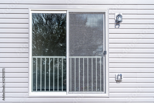 Slider verandah or porch door with railing and screen on a horizontal vinyl siding house 