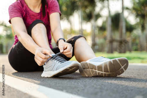 closeup of young woman runner tying her shoelaces. healthy and fitness concept. © Suriyawut