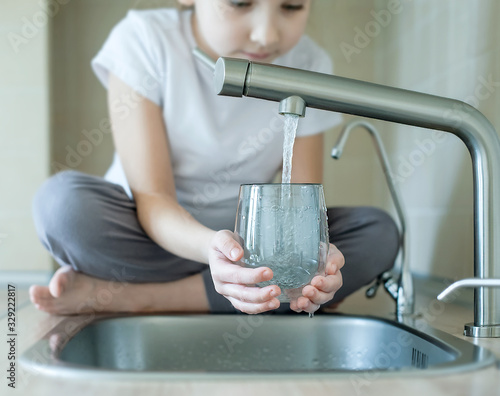 Child open water tap. Kitchen faucet. Glass of clean water. Pouring fresh drink. Hydration. Healthy lifestyle. Water quality check concept. World water monitoring day. Environmental pollution problem