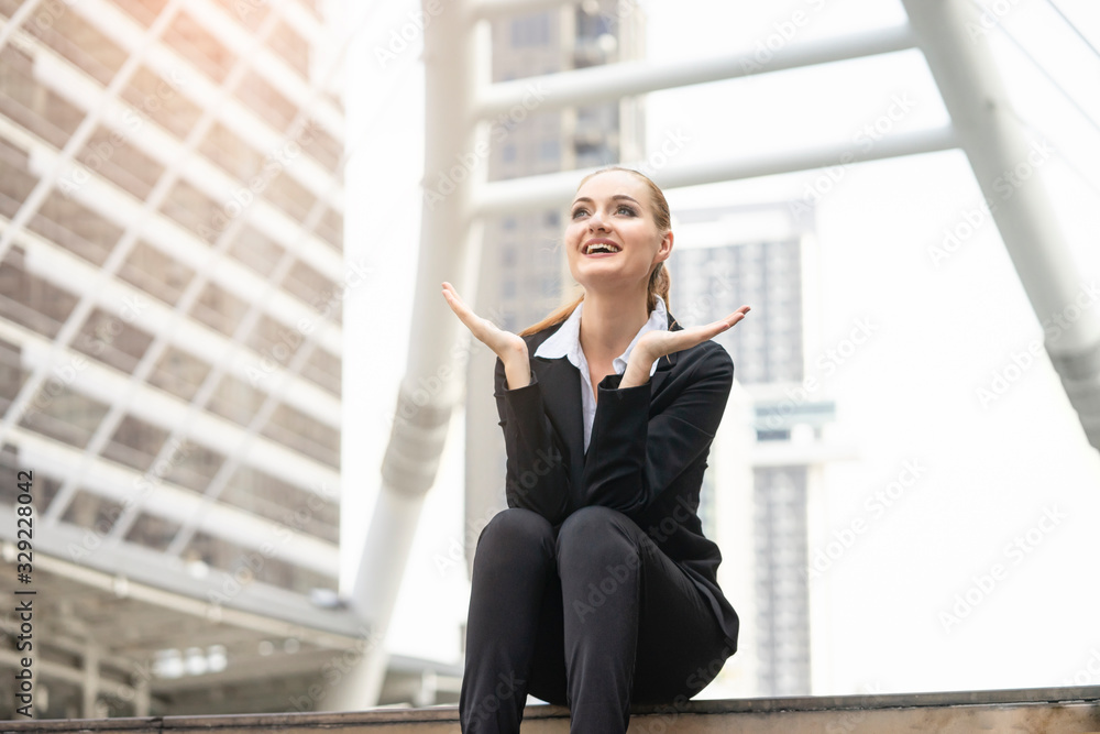 a businesswoman sitting on top of stairway with hands opened out and smiley face feeling overjoy, representing success or happiness in a workplace, in the city with modern architectural structure
