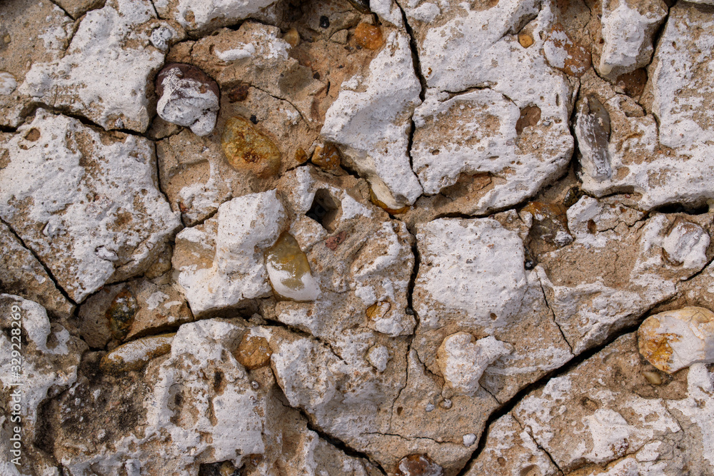 Old concrete wall with deep cracks. White paint, brown stones, bumps. Primary colors - Sorrell Brown, Alto. Old concrete wall with deep cracks. White paint, brown stones, bumps. Primary colors - Sorrell Brown, Alto.