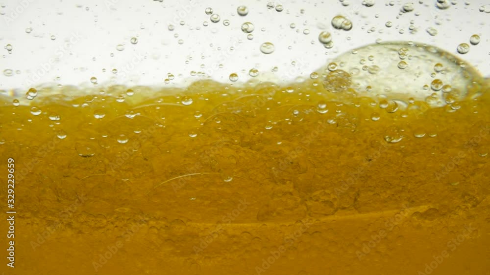 Golden color oil is poured into the tank, near view. Heterogeneous phase. The focus of boiling yellow oil is widespread, the bubble texture is a full frame and a macro of many different droplets. Golden color oil is poured into the tank, near view. Heterogeneous phase. The focus of boiling yellow oil is widespread, the bubble texture is a full frame and a macro of many different droplets.