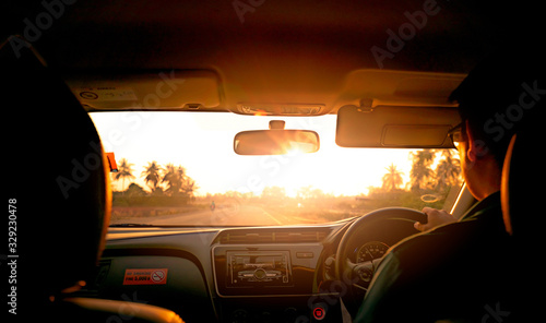 Back view of a man driving car for summer road trip travel. Car driving with safety on asphalt road. Driver hand holding steering wheel for control car. Inside view of car. Dashboard and windshield.