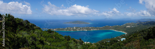 Panoramic view of a small bay on a remote Caribbean island with lush trees , aqua water and a blue sky with white clouds. © Brian