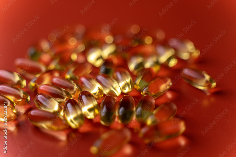 fish oil capsules on a red background close-up with a small roughness of sharpness. blurred background on the theme of health fish oil capsules on a red background close-up with a small roughness of sharpness. blurred background on the theme of health