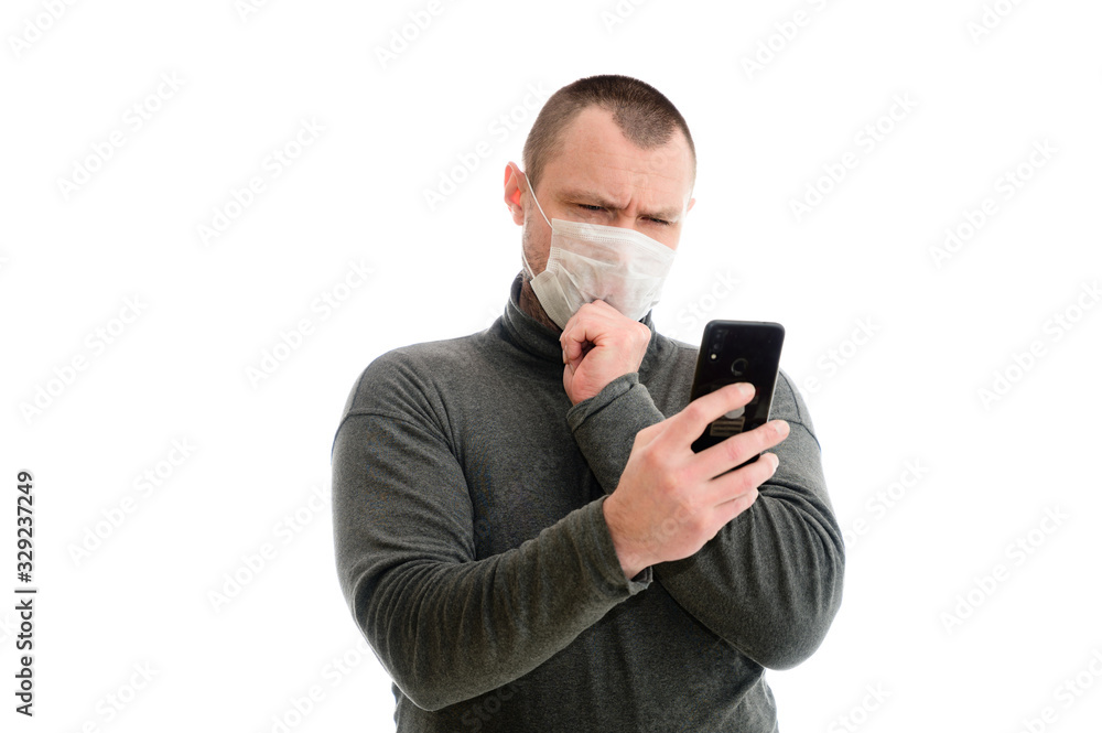 The model stands right in front of the camera. With smartphone shows emotions with hands concept isolate Caucasian man in a medical mask in a gray sweater on a white background The model stands right in front of the camera. With smartphone shows emotions with hands concept isolate Caucasian man in a medical mask in a gray sweater on a white background