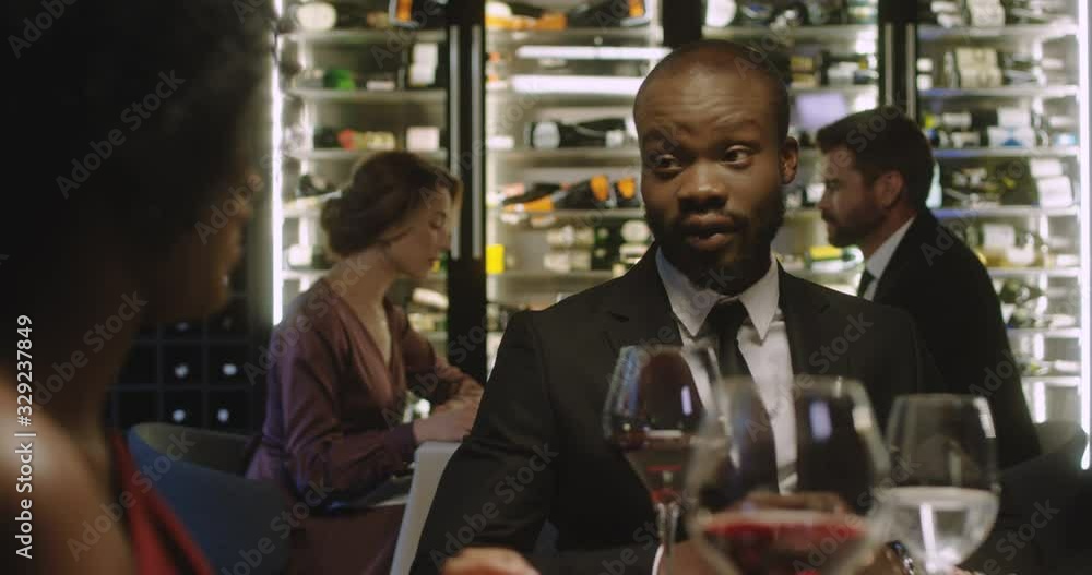 Close up of African American cheerful and happy attractive man and woman in love on date in restaurant having dinner with wine. Romantic evening of couple. Male and female clients talking and smiling. Close up of African American cheerful and happy attractive man and woman in love on date in restaurant having dinner with wine. Romantic evening of couple. Male and female clients talking and smiling.