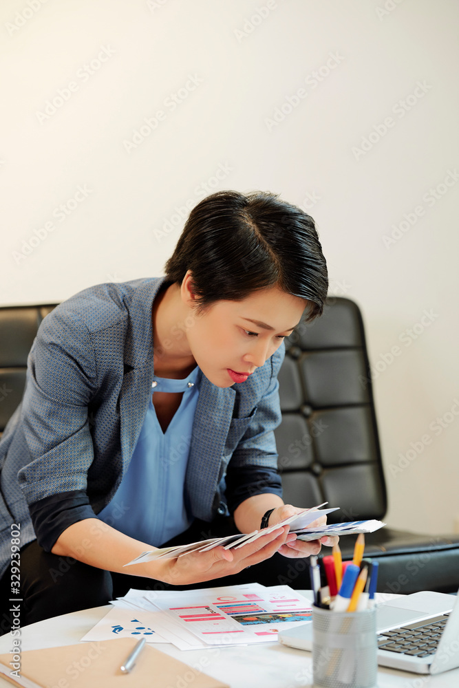 Female Vietnamese UI designer seaching for the perfect color in palette of samples Female Vietnamese UI designer seaching for the perfect color in palette of samples