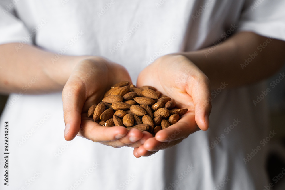 Almond in a womans hands. Almonds nuts is a healthy vegetarian protein and nutritious food. Nuts in a humans hand. Almond in a womans hands. Almonds nuts is a healthy vegetarian protein and nutritious food. Nuts in a humans hand.