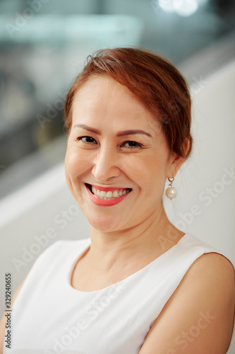 Portrait of happy smiling middle-aged Asian female entrepreneur looking at camera