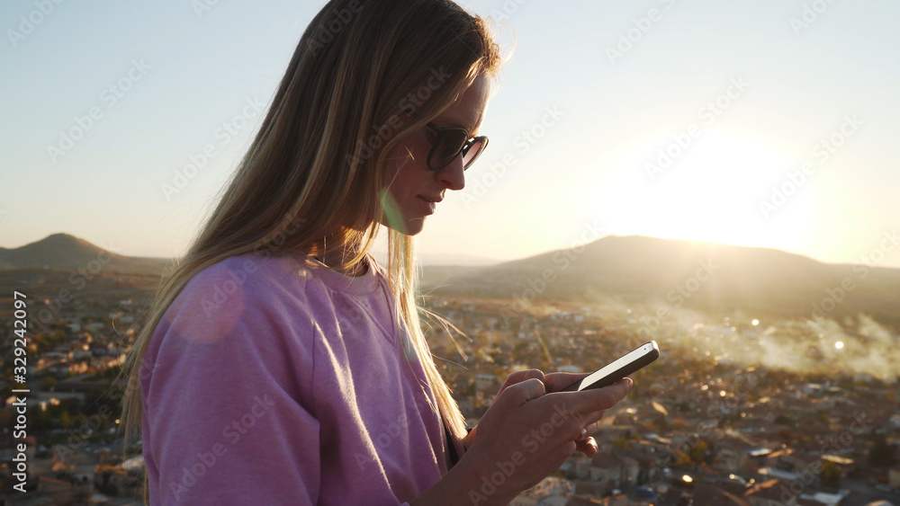 Naklejka premium Attractive young female using her smartphone with ancient city backgroung