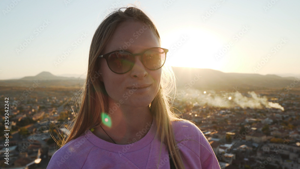 Young caucasian blonde female standing over ancient city and looking in camera Young caucasian blonde female standing over ancient city and looking in camera
