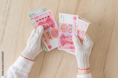 Chinese female hand in protective from coronavirus (virus) gloves counting money of south-east Asia. Сhina yuan (CNY) Currency of Hong Kong, Indonesia, Malaysia, Thai, Singapore dollar. photo