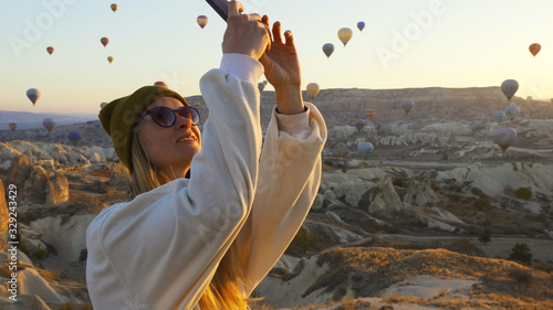 Young female taking pictures of air balloons by iphone