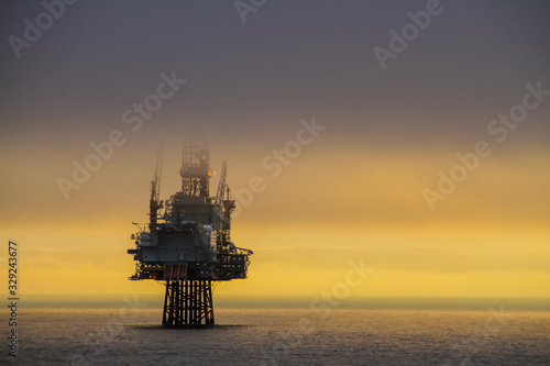 NORTH SEA, NORWAY - 2011 APRIL 15. Oil platform Ringhorn in the North Sea with low clouds cover the drilling tower with beautiful sunset in the background