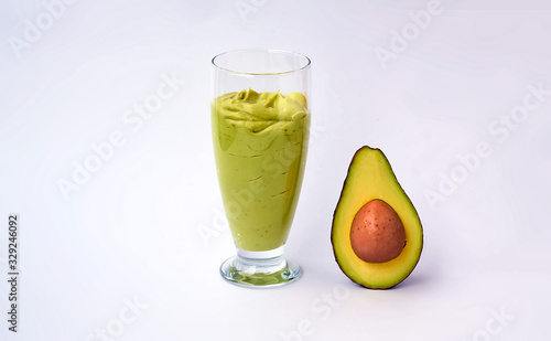 A glass of avocado and spinach smoothies and half an avocado on white background. Fitness product. Dietary sports nutrition.