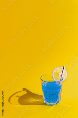 Crazy blue cocktail with lime and chia seeds in glass on orange background. Summer and vacation holidays concept. Vertical format. Copy space.