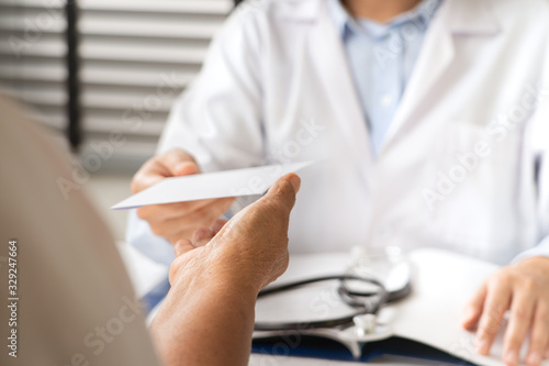 Doctor writing diagnosis and giving a medical prescription to senior women Patient