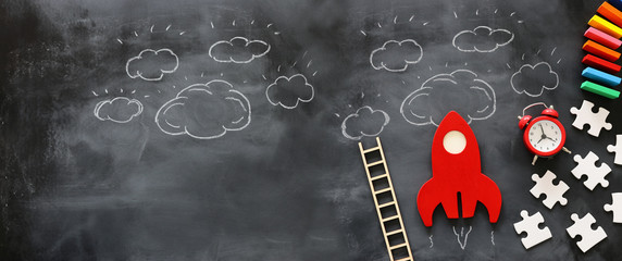 education or innovation concept. Wooden rocket over blackboard background. top view