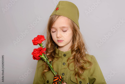 9 MAY. Beautiful little blonde girl kid with red carnation flowers for veterans. Victory Day. Memorial day. We remember! We are proud!