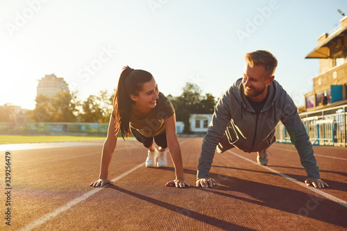 Plakat Young couple doing pushups in the stadium