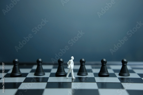 Business strategy conceptual photo - White people miniature of businessman walking in between of chess piece on a chessboard