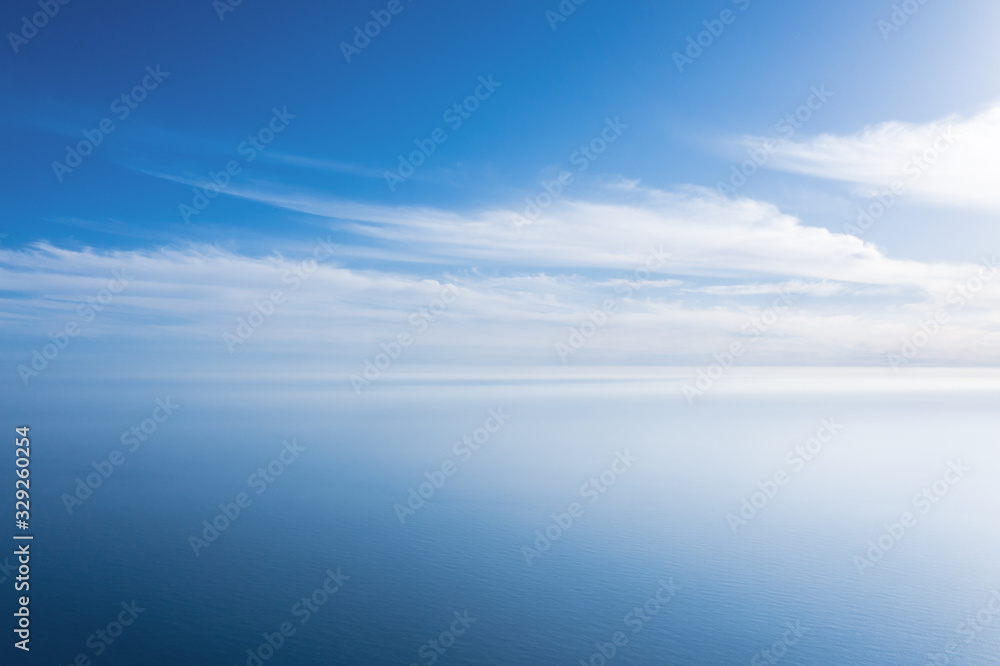 An aerial view of eternal blue sea or ocean with sunny and cloudy sky.