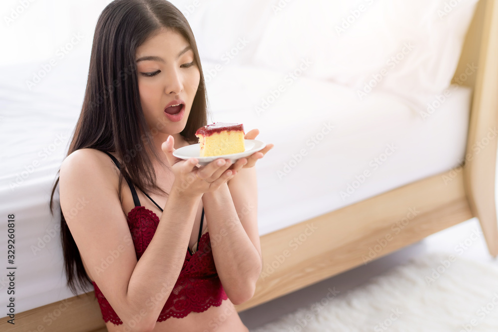 Attractive young sensual Asian woman eating strawberry cheeese cake at bed room in the morning Attractive young sensual Asian woman eating strawberry cheeese cake at bed room in the morning